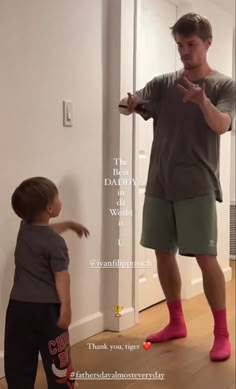 a man standing in front of a door talking to a little boy with pink socks