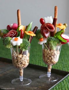 two vases filled with food on top of a metal tray next to green grass