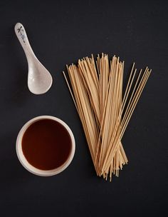 chopsticks, sauce and spoon on a black surface with an empty cup next to it