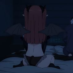 a woman sitting on top of a bed in a dark room with two bats hanging from the ceiling