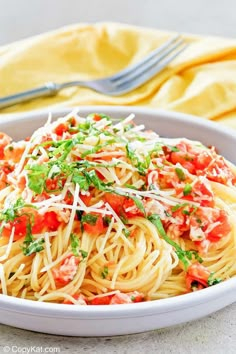 a white bowl filled with pasta and garnished with parmesan cheese on top