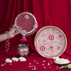 a woman is holding a decorative mirror next to other items on a red table cloth