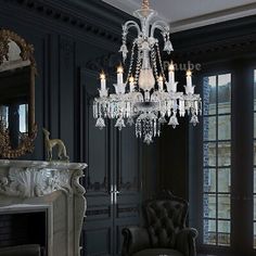 a chandelier hanging from the ceiling in a room with black walls and furniture