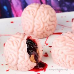 three brain - shaped treats are sitting on a plate with blood running down the surface