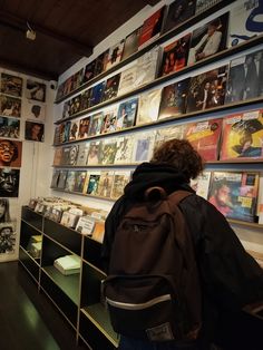 a person standing in front of a wall full of records and cds on display at a record store