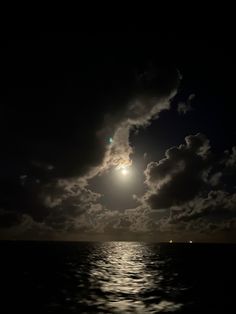 the moon is shining brightly in the dark sky over the ocean with clouds and water