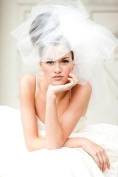 a woman wearing a veil on top of her head and sitting on a white bed