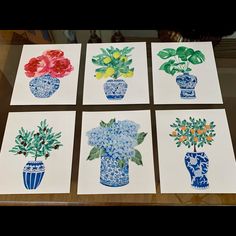 four cards with flowers in blue vases on top of a table next to each other