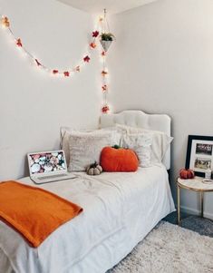 a white bed topped with pillows and blankets next to a night stand filled with pictures