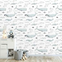 a room with a wallpaper that has whales on it and a stuffed animal in the corner