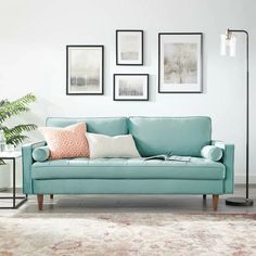 a living room with a blue couch and pictures on the wall above it, along with a rug