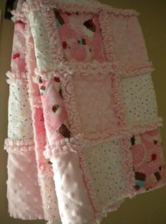 a pink blanket hanging from the side of a wall with cupcakes on it