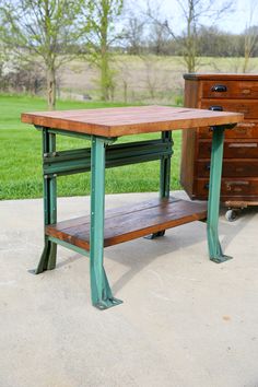 a wooden table sitting on top of a cement floor next to a chest of drawers