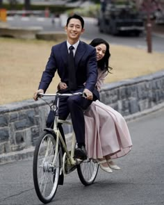 a man and woman riding on the back of a bike