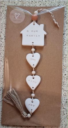 a white ceramic house ornament hanging from a string on top of a piece of brown paper