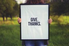 a person holding up a sign that says give thanks