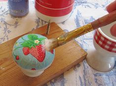 someone is painting a cupcake with strawberries on it and holding a paintbrush