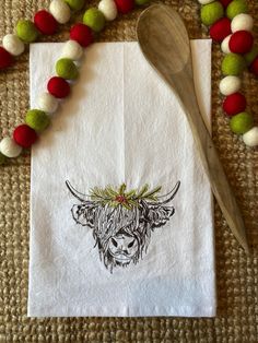 a napkin with a cow on it next to a spoon and some pom - poms