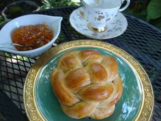 a plate topped with a croissant on top of a table next to cups and saucers