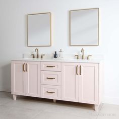 two mirrors on the wall above double sinks in a white bathroom with gold trimmings