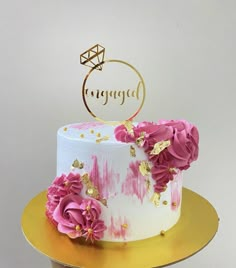 a white and pink cake with gold decorations