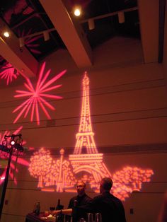 two people sitting at a table in front of a projection of the eiffel tower