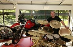 a man standing next to a motorcycle and drums