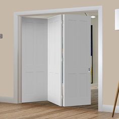 an open white door in the middle of a room with wood flooring and beige walls