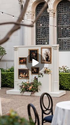 an outdoor area with tables, chairs and pictures on the wall in front of it