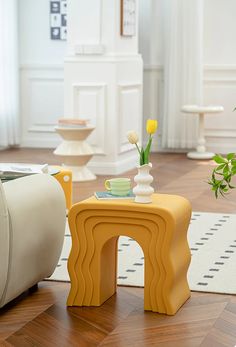 a yellow table sitting on top of a hard wood floor next to a white chair