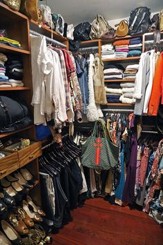 a closet filled with lots of different types of clothes and handbags on top of wooden shelves