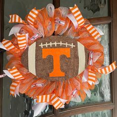 an orange and white football wreath with the letter t on it's front door