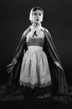 an old photo of a woman wearing a dress and cape with the letter j on it