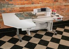 a sewing machine sitting on top of a white table next to a brick wall and black and white checkered floor