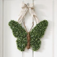 a white door with a butterfly shaped wreath hanging on it's side and ribbon tied around the top