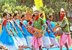 several women in colorful outfits are walking down the street with baskets on their heads and drums