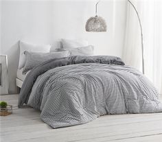 a bed with black and white striped comforter next to a lamp on the floor