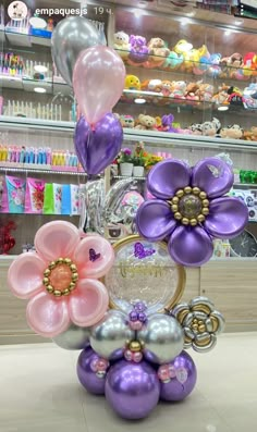 some balloons are in the shape of flowers and hearts on display at a storefront