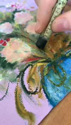 someone is using a marker to paint flowers on a piece of paper with watercolors