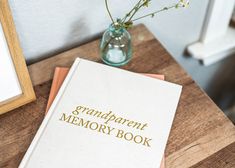 a book sitting on top of a wooden table next to a vase with flowers