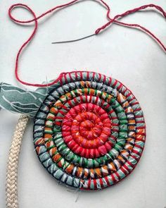 an ornament made out of beads on a white surface with red string and thread