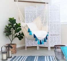 a white hammock hanging from the ceiling in a room with blue and white rugs