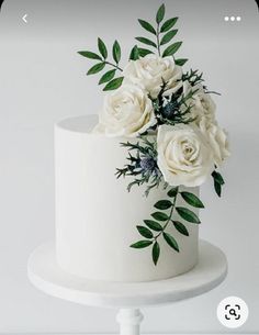 there is a white cake with flowers on the top and green leaves on the bottom