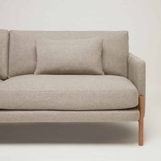 an upholstered couch with pillows on the back and arms, in light grey fabric