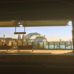 people sitting on benches in front of a bridge and the sydney harbour with opera house in the background