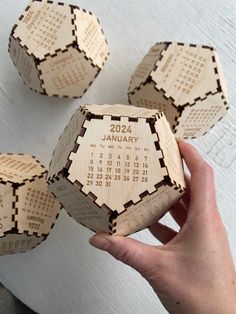 a person holding three wooden calendars in their hands