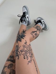 a woman's legs with tattoos and sneakers on