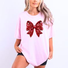 Add Festive Flair with Our Red Faux Glitter Bow T-Shirt!  Looking to make a bold holiday statement this season? Our Red Faux Glitter Bow Print T-shirt is the perfect blend of style, comfort, and festive fun! Made from 100% cotton, this tee offers a soft and breathable fit that's perfect for casual everyday wear or dressed-up holiday parties. With a trendy faux glitter bow design, this shirt adds a splash of sparkle to your wardrobe without any mess. Whether you're celebrating at a Christmas part Holiday Skirts, Bow Women, Holiday Apparel, Bow Print, Novelty Shirts, Holiday Sparkle, Glitter Print, Christmas Bow, Glitter Bow