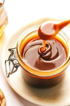 a spoon is pouring caramel sauce into a bowl