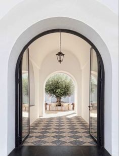 an archway leading to a dining area with a tree in the center